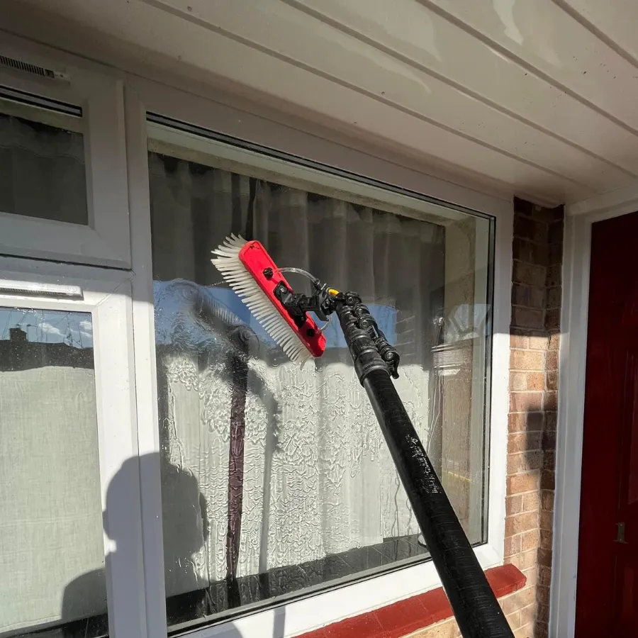 Exterior residential window being cleaned with a water-fed brush