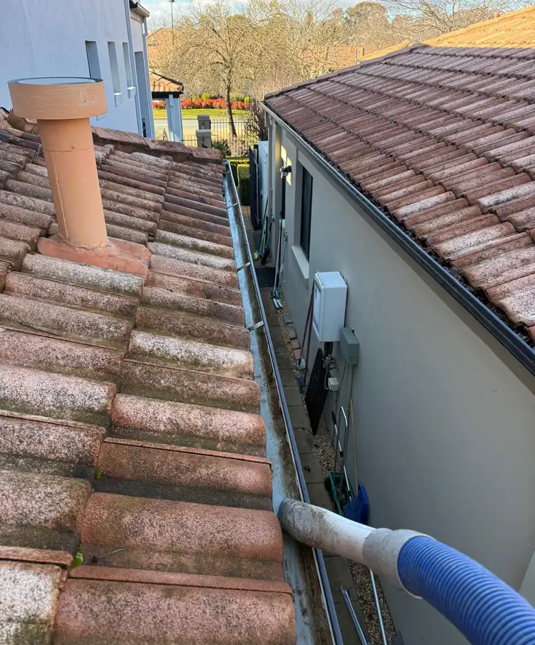 Gutter vacuum hose positioned along a tiled Canberra roofline